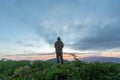 Male tourists stand on top of a mountain in the morning looking at the beautiful view of the twilight as the sun rises on the