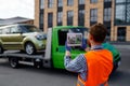 Male tow truck assistant photographing loaded car Royalty Free Stock Photo