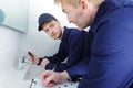 male trainee plumber working on tap in bathroom Royalty Free Stock Photo