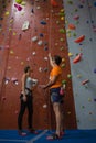 Male trainer assisting female athlete in climbing wall at gym Royalty Free Stock Photo