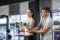 Male trainer assisting woman lifting dumbbells Royalty Free Stock Photo
