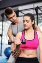 Male trainer assisting woman lifting dumbbells Royalty Free Stock Photo