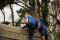 Male trainer assisting woman to climb a wooden wall Royalty Free Stock Photo