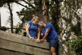 Male trainer assisting woman to climb a wooden wall Royalty Free Stock Photo