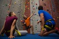 Male trainer guiding athletes in wall climbing at gym Royalty Free Stock Photo