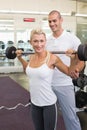 Male trainer helping woman with lifting barbell in gym Royalty Free Stock Photo