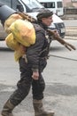 A male tramp walks down a street in the city and carries all his clothes, food, and sleeping space in bags