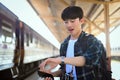 Male traveler with backpack checking time while waiting for train at platform. Royalty Free Stock Photo