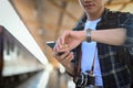 Male traveler holding mobile phone and checking time on wrist watch while waiting for her train at platform Royalty Free Stock Photo