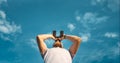 Male Traveler Looking Through Binoculars In The Distance Against The Sky. Low Angle Point Shoot