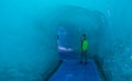 Male traveler observes the icy walls as he walks through a melting glacier.