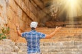 Male traveler in a plaid shirt and shorts explores the ruins of an ancient building at the entrance to the arch with bright light Royalty Free Stock Photo