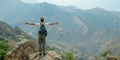 A male traveler with raised hands standing stands on the top of a mountain with white fog below. Royalty Free Stock Photo