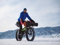 A male traveler rides a fatbike on a frozen mountain lake