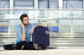 Male traveler sitting on floor talking on mobile phone