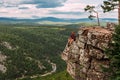 A male traveler is sitting on a rock with a bird`s-eye view of the forest. The concept of recreation and tourism. A man traveler Royalty Free Stock Photo