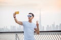 Male traveler takes a selfie on his smartphone against the backdrop of the skyscrapers of Dubai and the Creek Channel Bay