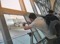 Male traveler using mobile phone to take photo of an airplane parking at jet bridge, waiting for passenger to board at airport.