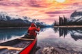 Male traveler in winter coat rowing a red canoe in Spirit Island on Maligne Lake at the sunset Royalty Free Stock Photo