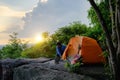 Male Travelers Pitch Vibrant Orange Tent on Cliff with a Natural View, Embracing Pristine Natural Views or Surrounded by Cliffside