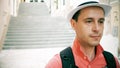 Sad male traveller wearing hat walks downstairs on the street