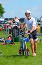 Male triathlete at end of cycling stage with bicycle.