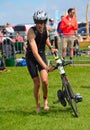 Male triathlete at end of cycling stage with bicycle.