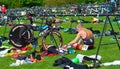 Male triathlete at end of cycling stage sitting on the ground with bicycles.