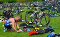 Male triathlete at end of cycling stage sitting on the ground with bicycles.