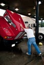 Male truck driver closing hood of 18-wheeler