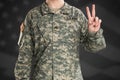 Male in US Army soldier uniform shows hand sign of victory