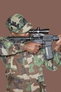Male US Marine Corps soldier aiming M4 assault rifle over brown background Royalty Free Stock Photo
