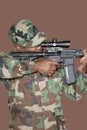 Male US Marine Corps soldier aiming M4 assault rifle over brown background