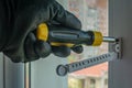 Male using screwdriver tightens screw that fixes plastic window opening limiter Close-up of gloved hand with screwdriver Royalty Free Stock Photo