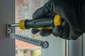 Male using screwdriver tightens screw that fixes plastic window opening limiter Close-up of gloved hand with screwdriver Royalty Free Stock Photo