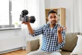 Male video blogger with camera blogging at home