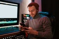 Male Video Editor sitting at his Computer using phone Royalty Free Stock Photo