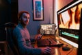 Male Video Editor sitting at his Computer using phone Royalty Free Stock Photo