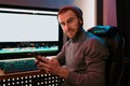 Male Video Editor sitting at his Computer using phone Royalty Free Stock Photo