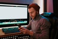 Male Video Editor sitting at his Computer using phone Royalty Free Stock Photo