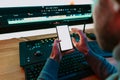 Male Video Editor sitting at his Computer using phone blank screen Royalty Free Stock Photo