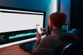 Male Video Editor sitting at his Computer using phone blank screen Royalty Free Stock Photo