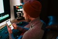 Male Video Editor sitting at his Computer using phone blank screen Royalty Free Stock Photo