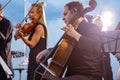 Male violoncellist playing in orchestra at outdoor concert