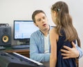 Male vocal coach teaching little girl how to sing. Royalty Free Stock Photo