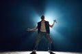 Male vocalist in denim singing to audience against cool, moody blue stage lighting. Singer gesturing rock sign. Royalty Free Stock Photo