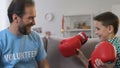 Male volunteer realizing dream of little boy orphan, presenting boxing gloves