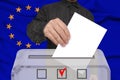 Male voter drops a ballot in a transparent ballot box against the background of the European Union national flag, concept of state Royalty Free Stock Photo