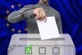 Male voter drops a ballot in a transparent ballot box against the background of the European Union national flag, concept of state Royalty Free Stock Photo