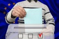 Male voter drops a ballot in a transparent ballot box against the background of the European Union national flag, concept of state Royalty Free Stock Photo